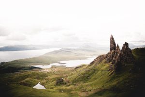 A tall, pointed rock formation jutting out over fields of verdant green.