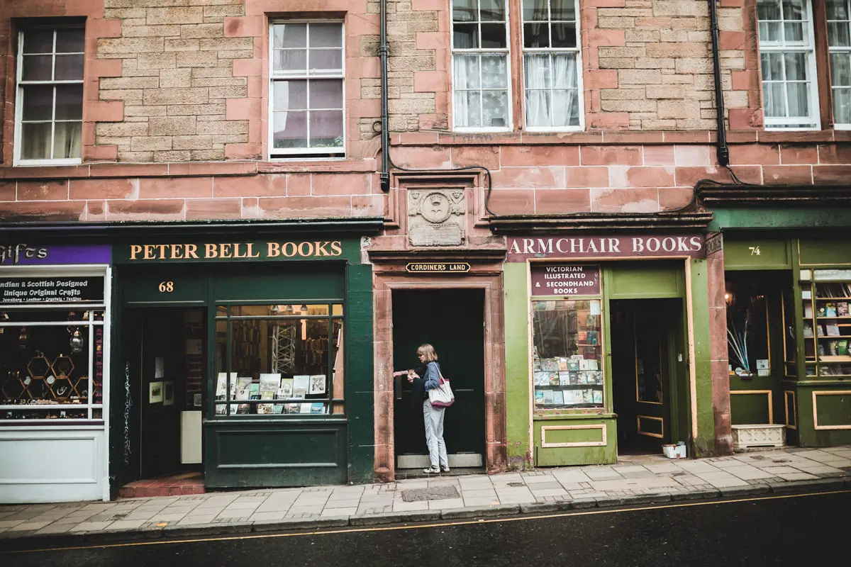 A women unlocks a door nestled between two bookshops in Edinburgh.