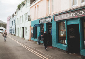 Two men stand outside of a blue restaurant in Portree, Scotland