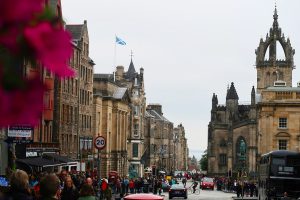 a cobblestone road lined with historic buildings and cathedrals is flocked with pedestrians on a 3 days in Edinburgh itinerary