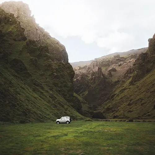 A silver Suzuki Jimney parked at Pakgil, the best campsite in Iceland shrouded in emerald.