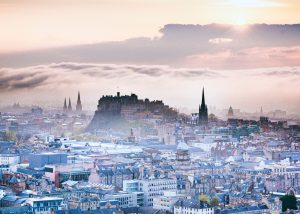 View of Edinburgh skyline at sunrise with Edinburgh Castle and spires in mist, promoting guide to the best hostels in Edinburgh