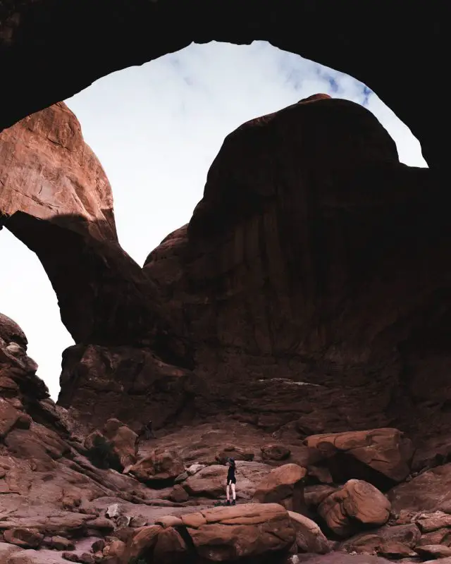 person standing under a rock arch - double arch