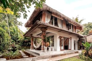 A neutral-toned, one bedroom villa that appears to be designed for an artists retreat. The thatched roof and hammock on the bottom deck create a peaceful aura at this zen stay in Ubud.