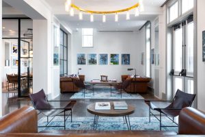 In one of the best areas to stay in Dallas, the Kimpton Pittman Hotel lobby exudes historic charm paired with modern industrial design, showcasing large windows, warm wood accents, and stylish, contemporary furnishings