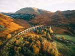 Glenfinnan Viaduct on the Isle of Skye, Scotland, surrounded by autumn colors — a magical spot to experience Scotland on a budget, especially when visiting in the off-peak season to save money.