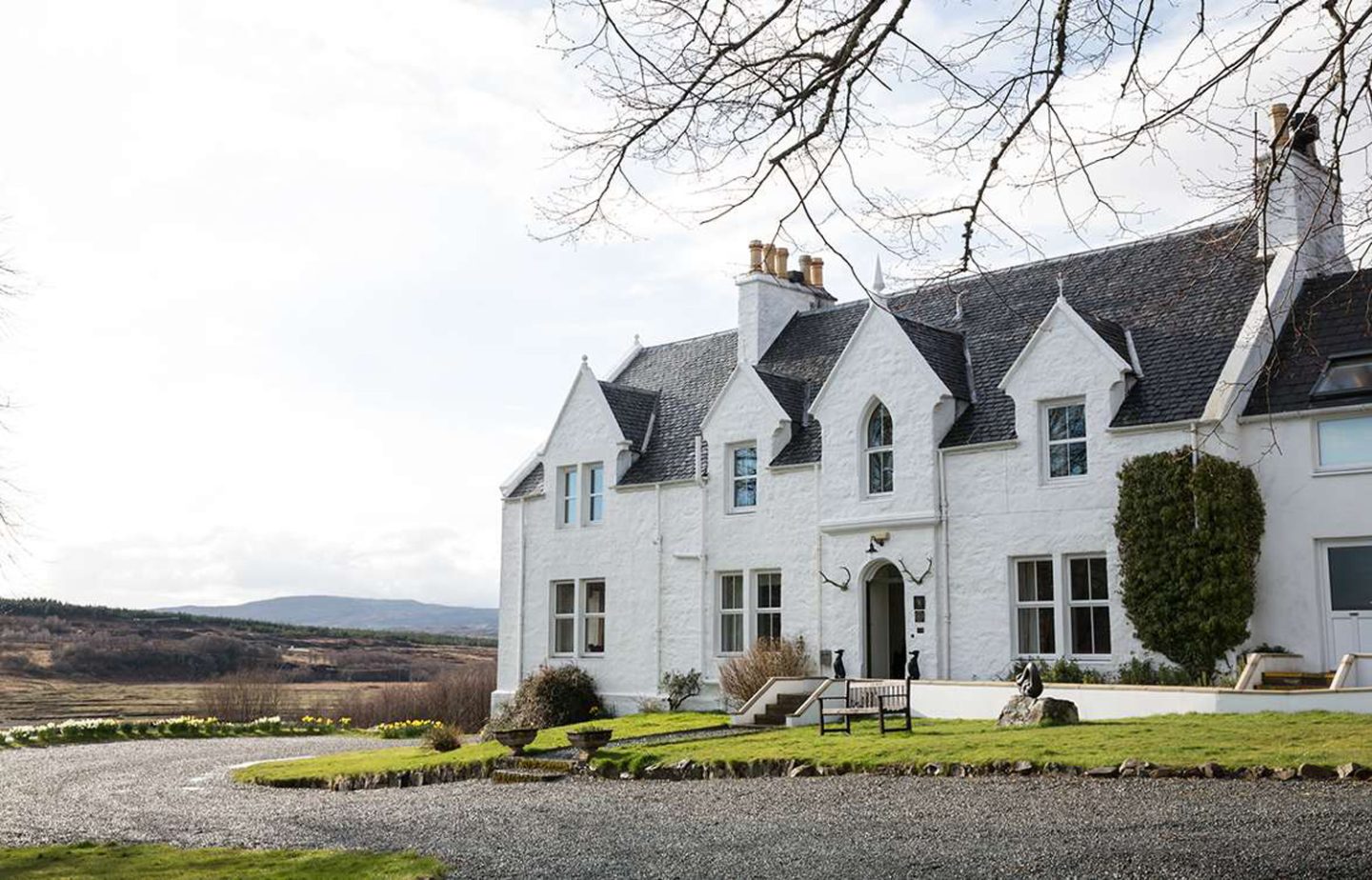 Exterior view of Kinloch Lodge, a luxury white hotel and restaurant, one of the best places to stay on the Isle of Skye, Scotland.
