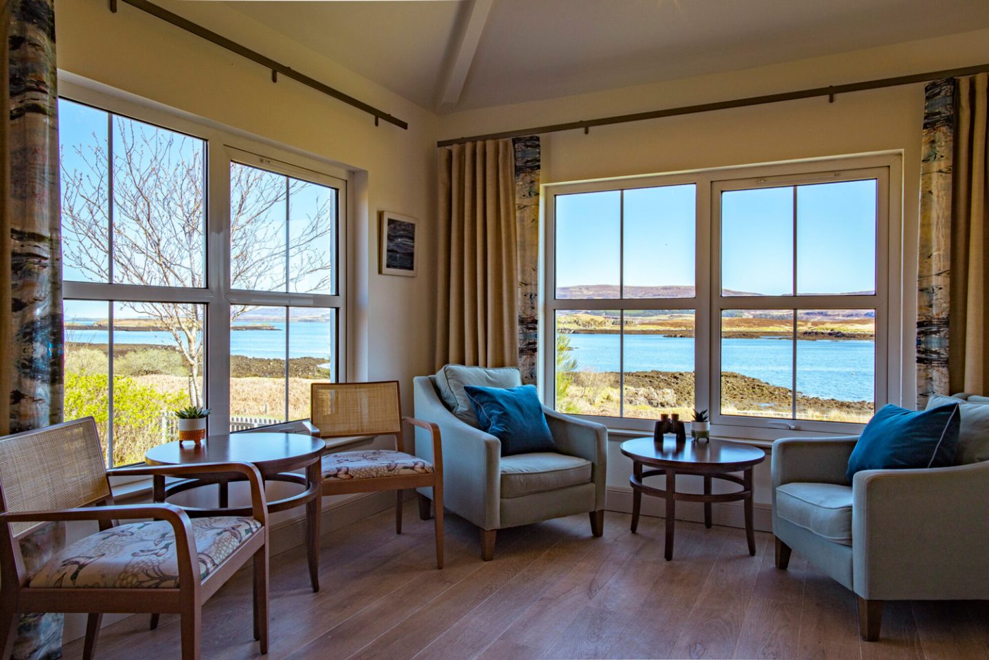 Interior of a luxury suite in The House Over-By accommodation at The Three Chimneys, Isle of Skye, with large windows overlooking the beautiful coastal loch and shoreline.