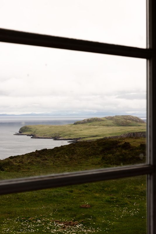 Green peninsula and distant mountains framed by the bothy's window.